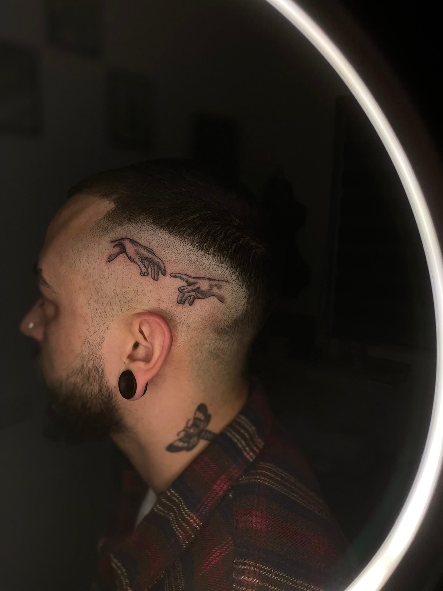 The Creation of Adam hands, fine-line dotwork on the side of the head — by Stefan Buttigieg at Ink Alley, Żabbar