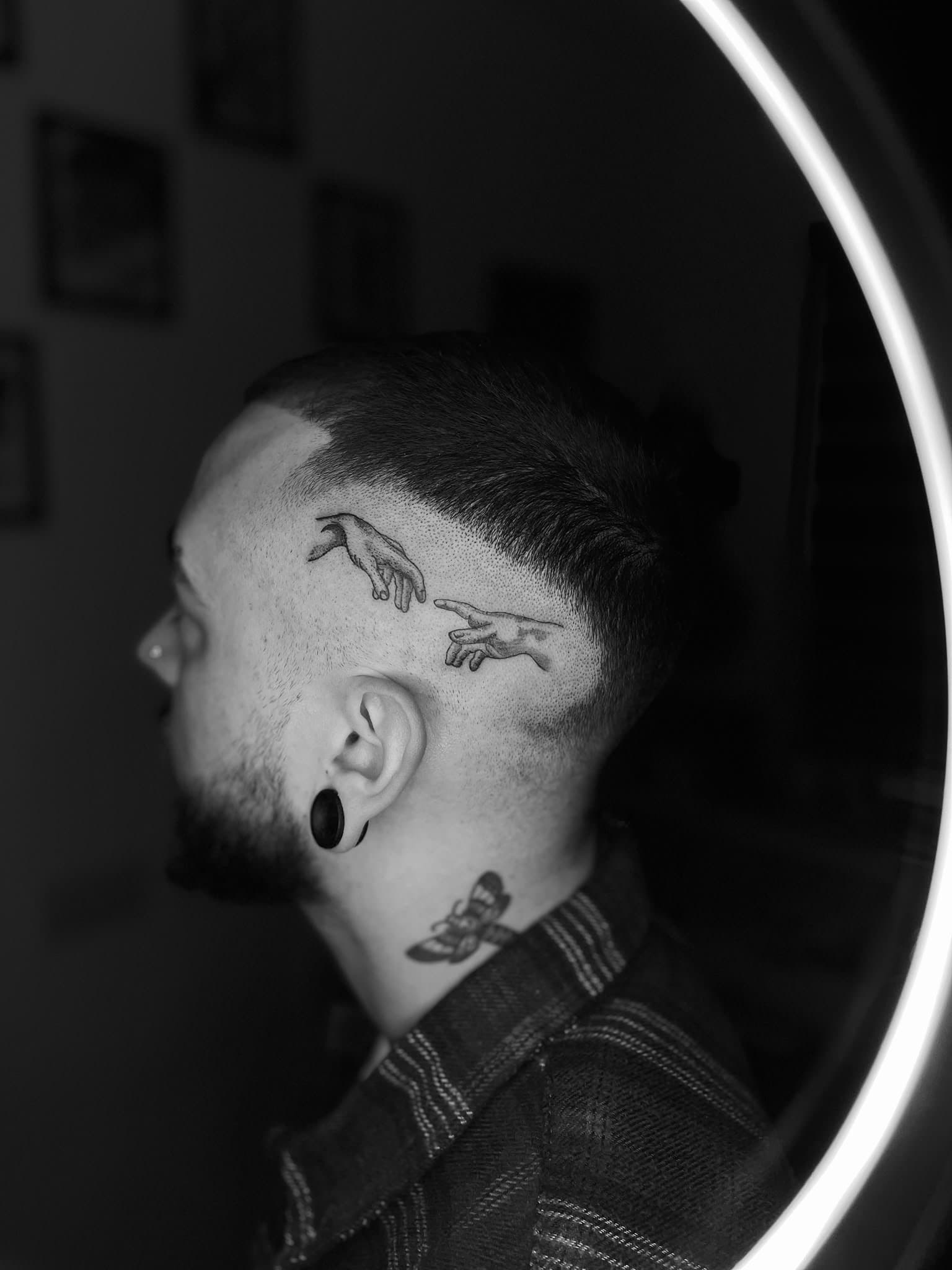 The Creation of Adam hands, fine-line dotwork above the ear — by Stefan Buttigieg
